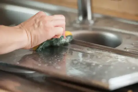 Dłoń czyści aluminiową powierzchnię gąbką. Dowiedz się, czym wyczyścić aluminium, aby lśniło jak nowe.